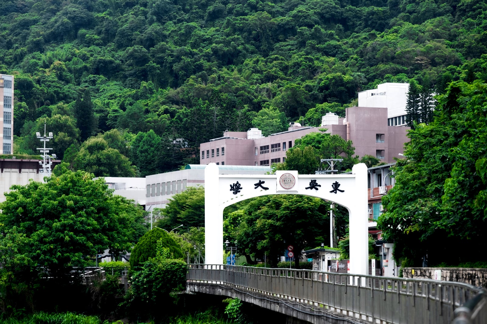 Soochow University campus gate beside tree-covered hills in Taipei